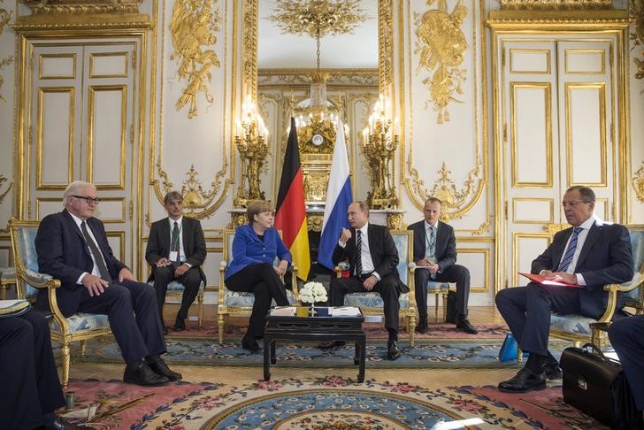 © Reuters. German Chancellor Angela Merkel sits with Russian President Vladimir Putin during a bilateral meeting prior to a summit on Ukraine at the Elysee Palace in Paris