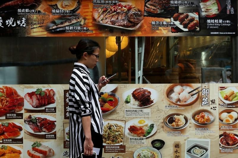 © Reuters. A woman checks her smartphone outside a restaurant at Tsim Sha Tsui shopping district in Hong Kong