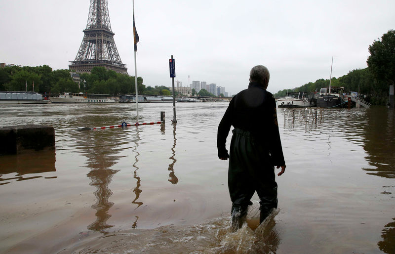 © Reuters. Homem andando em rua alagada ao lado da torre Eiffel, em Paris