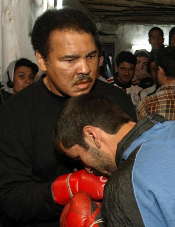 © Reuters. Foto de archivo de un boxeador afgano besando los guantes del legendario Muhammad Ali tras una práctica en un club de Kabul