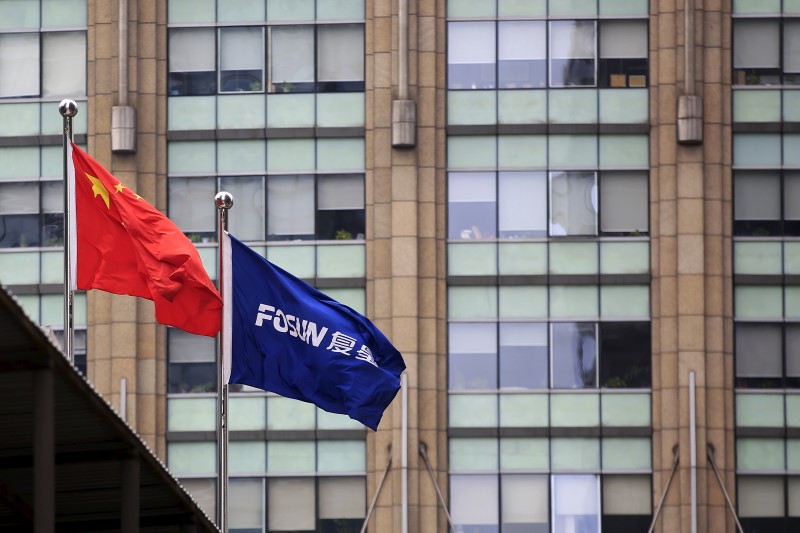 © Reuters. A Chinese national flag flies in front of a building of the headquarters of Fosun International, in Shanghai