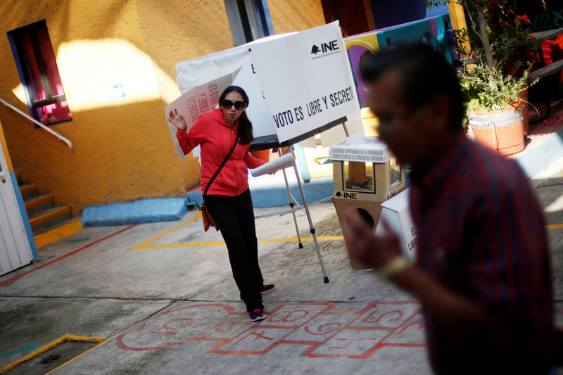 © Reuters. A woman leaves a booth to cast her ballot during the election of 60 deputies, to form the Constituent Assembly that will create a constituition for Mexico City