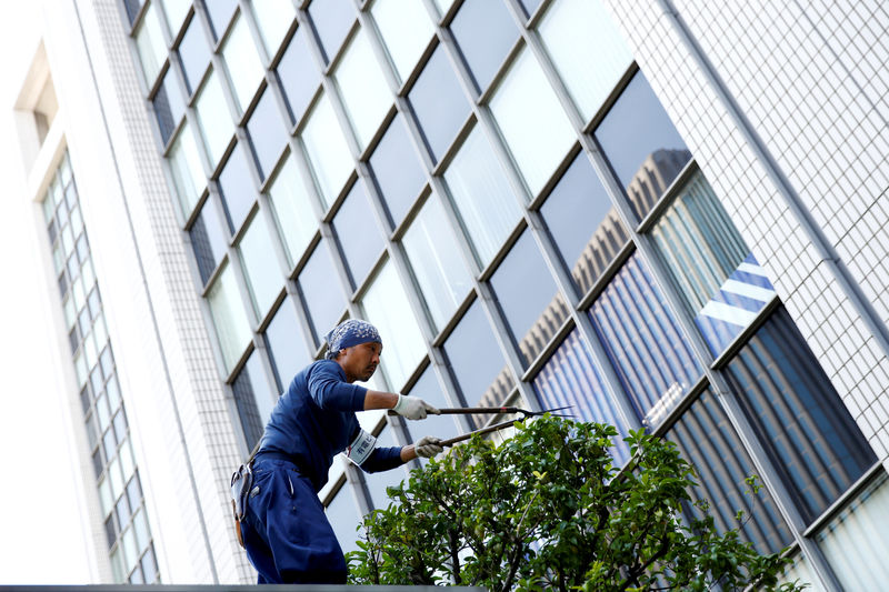 © Reuters. A worker cuts a tree in front of an office building at a business district in Tokyo