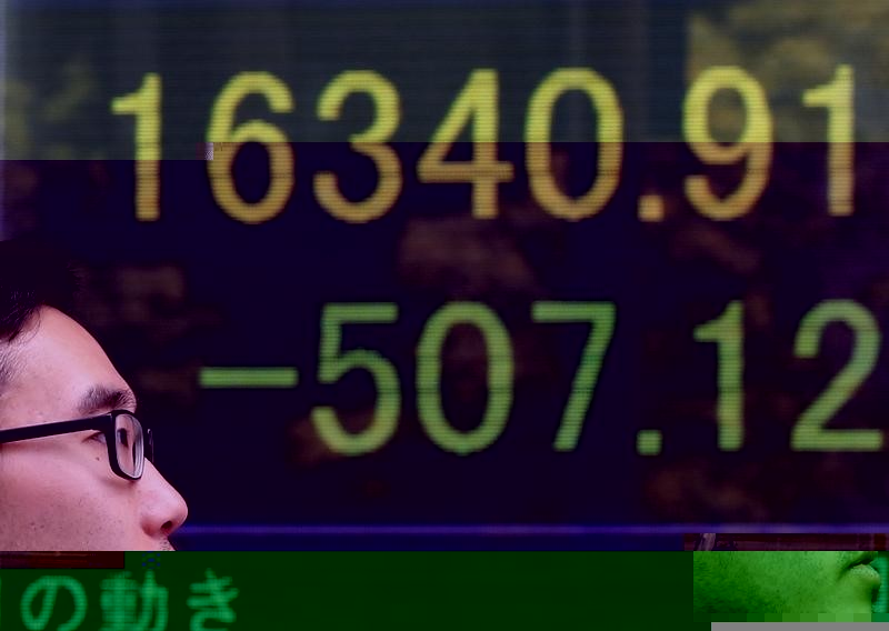 © Reuters. People are reflected in a screen displaying the Nikkei average outside a brokerage in Tokyo