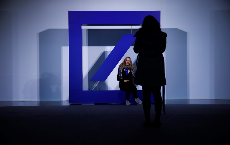 © Reuters. People pose for pictures with the emblem of Deutsche Bank during the bank's annual general meeting in Frankfurt