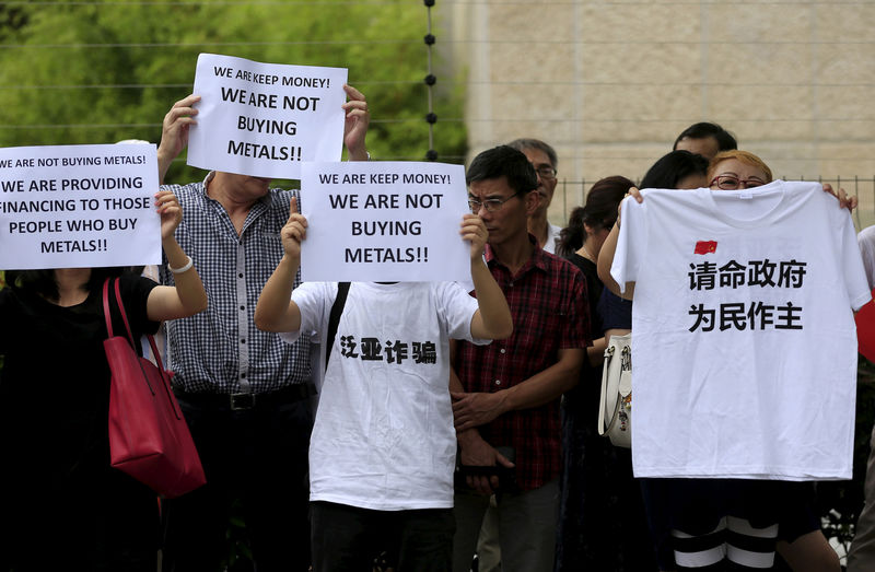 © Reuters. Protesters holding signs gather outside the Shanghai Banking Regulatory Bureau to protest against the Fanya Metal Exchange in Shanghai