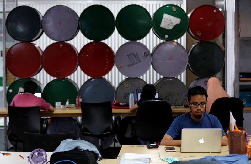 © Reuters. Employees work at their desks at Mediatrac in Jakarta