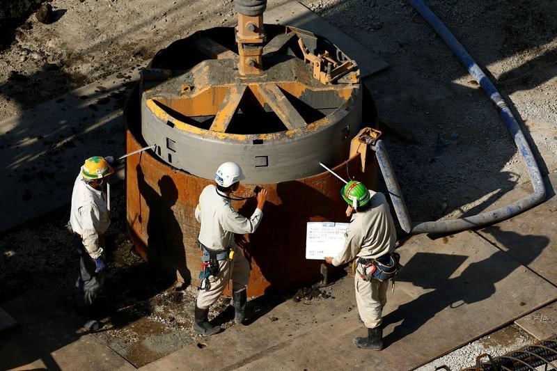 © Reuters. Workers take measurements at a construction site in central Tokyo