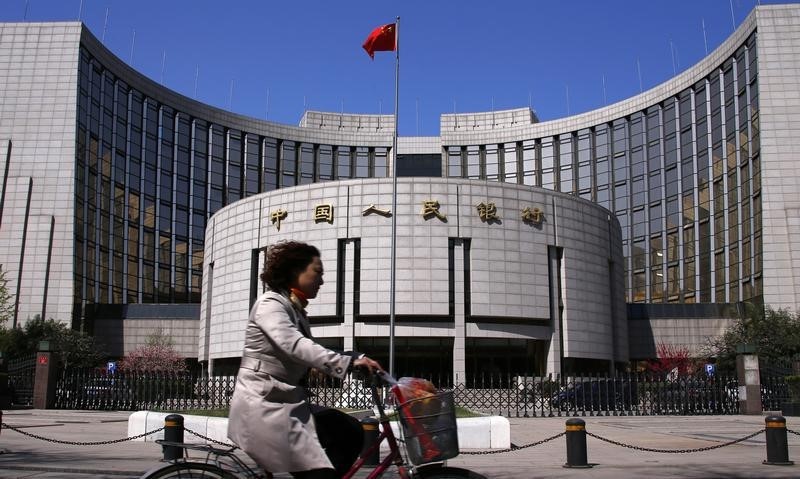 © Reuters. A woman rides past the headquarters of the People's Bank of China, the central bank, in Beijing
