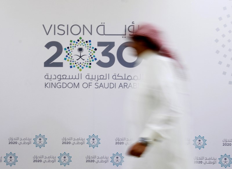 © Reuters. A Saudi man walks past the logo of Vision 2030 after a news conference in Jeddah