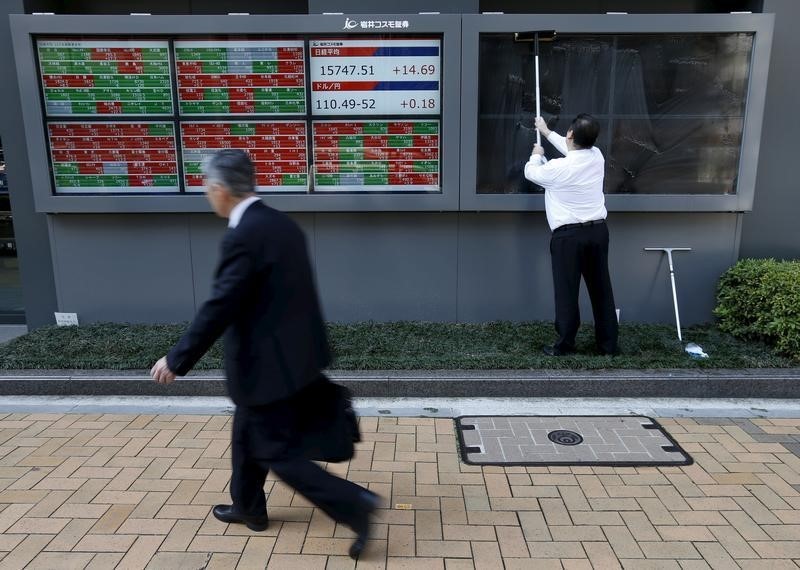 © Reuters. A man cleans electronic boards showing the Japan's Nikkei average, the exchange rate between Japanese yen against the U.S. dollar and stock quotation outside a brokerage in Tokyo