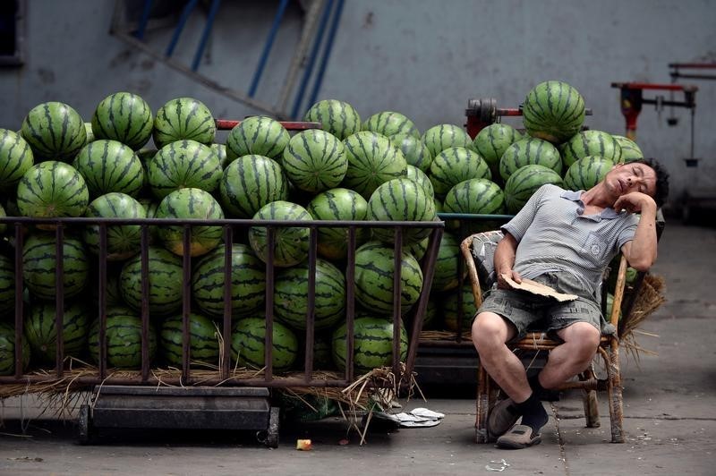 © Reuters. A vendor selling watermelons naps as he waits for customers at a market in Taiyuan
