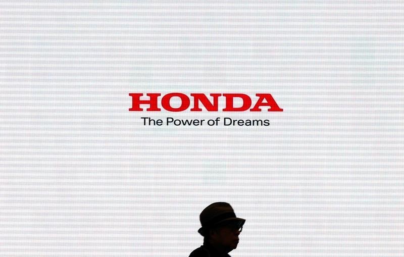 © Reuters. Man is silhouetted against a logo of Honda Motor at the company showroom in Tokyo