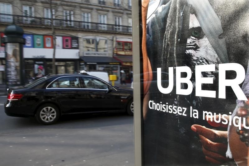 © Reuters. File photo shows a taxi passing by an advertisement for the Uber car and ride-sharing service displayed on a bus stop in Paris