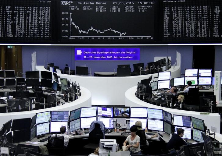 © Reuters. Traders work at their desks in front of the German share price index, DAX board, at the stock exchange in Frankfurt