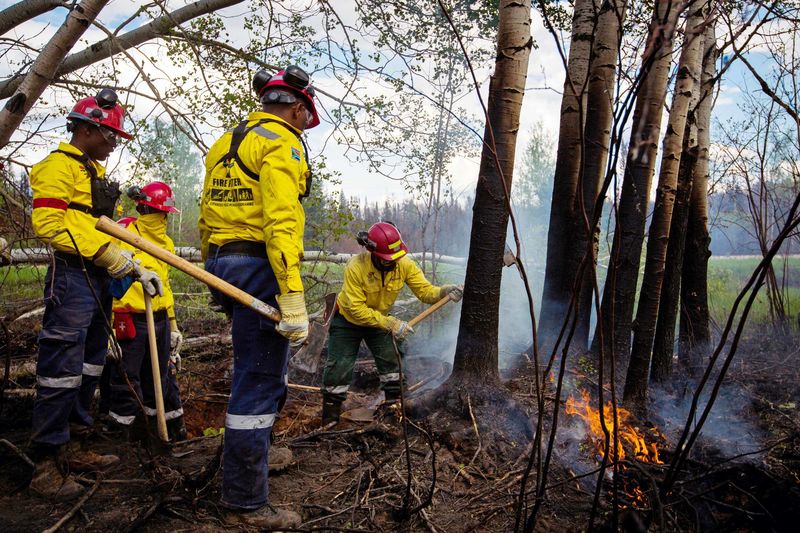 © Reuters. South African firefighters work to remove hotspots from a massive wildfire around Fort McMurray, Canada