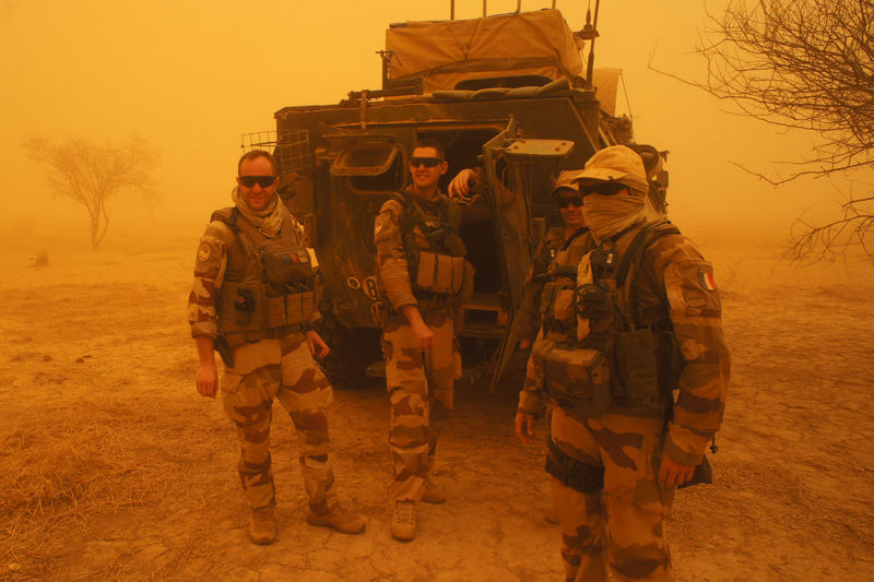 © Reuters. French soldiers from Operation Barkhane stand outside their armored personnel carrier during a sandstorm in Inat