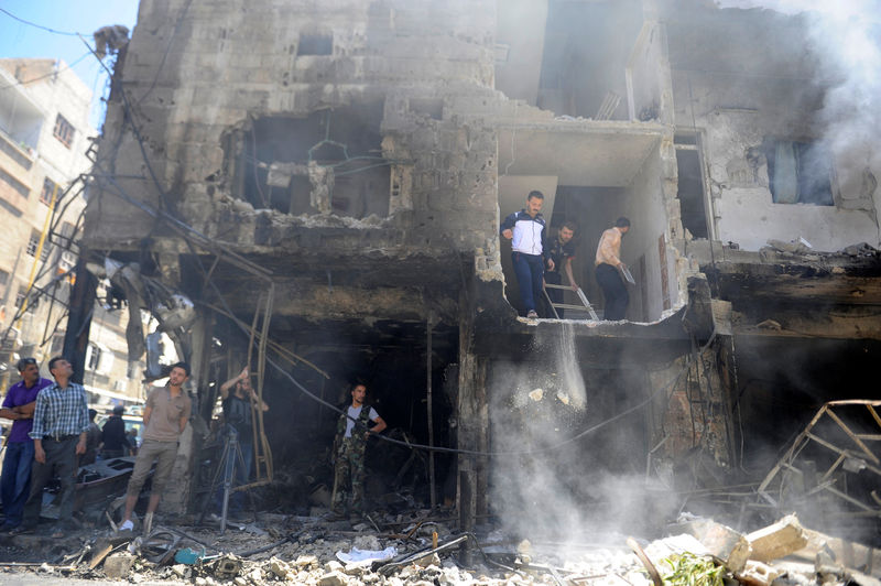 © Reuters. People and Syrian Army members inspect a damaged site after a suicide and car bomb attack in south Damascus Shi'ite suburb of Sayeda Zeinab