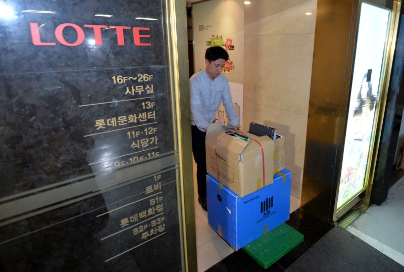 © Reuters. An investigator from the prosecution office carries boxes containing confiscated articles at Lotte Group's headquarters in Seoul