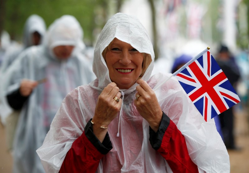© Reuters. Guests wear transparent waterproofs as they gather on the Mall for the Patron's Lunch, an event to mark Britain's Queen Elizabeth's 90th birthday, in Londo