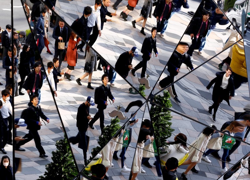 © Reuters. People are reflected in mirrors as they walk in a busy shopping district in Tokyo, Japan