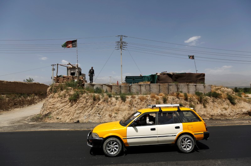 © Reuters. An Afghan policeman keeps watch at a check post on a highway, north of Kabul