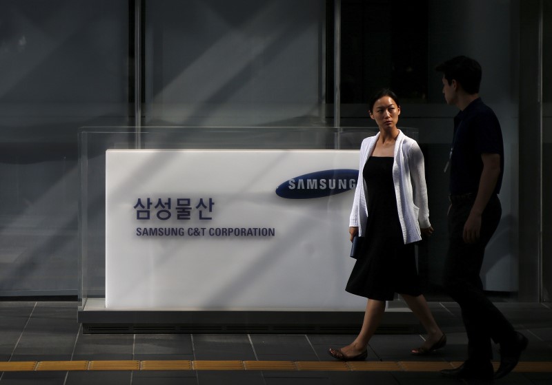 © Reuters. Employees walk past a logo of Samsung C&T Corp at the company's headquarters in Seoul, South Korea