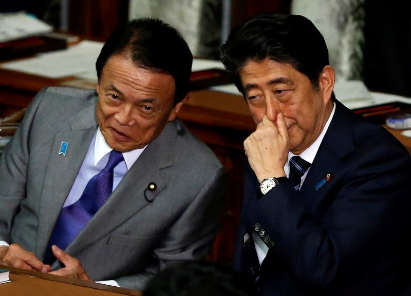 © Reuters. Japan's PM Abe and DPM and Finance Minister Aso talk before the lower house defeat a no-confidence motion against Abe's cabinet, submitted by four opposition parties at the parliament in Tokyo