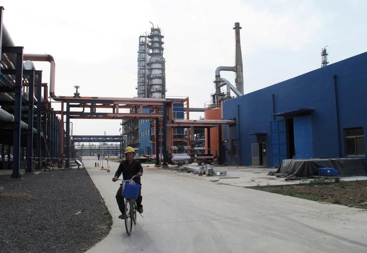 © Reuters. An employee rides a bike on a road near refinery plants of Chambroad Petrochemicals, in Boxing