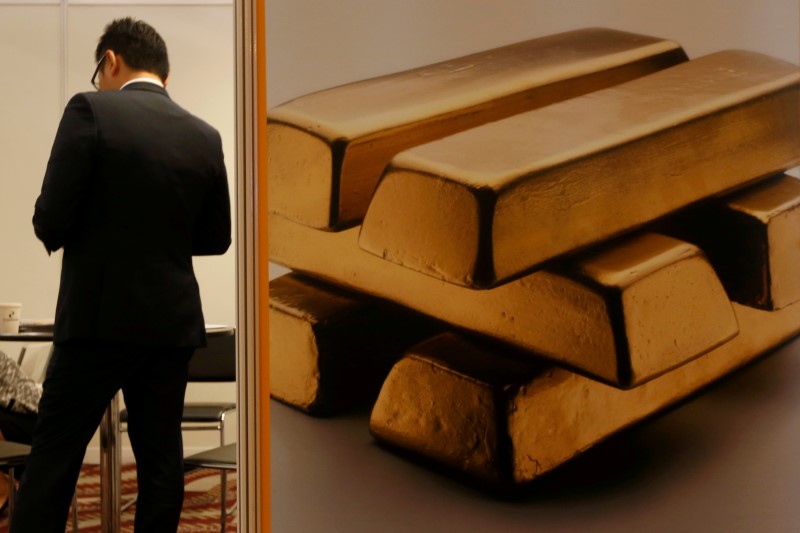 © Reuters. A participant stands beside an illustration of gold at a booth during LME Week Asia in Hong Kong