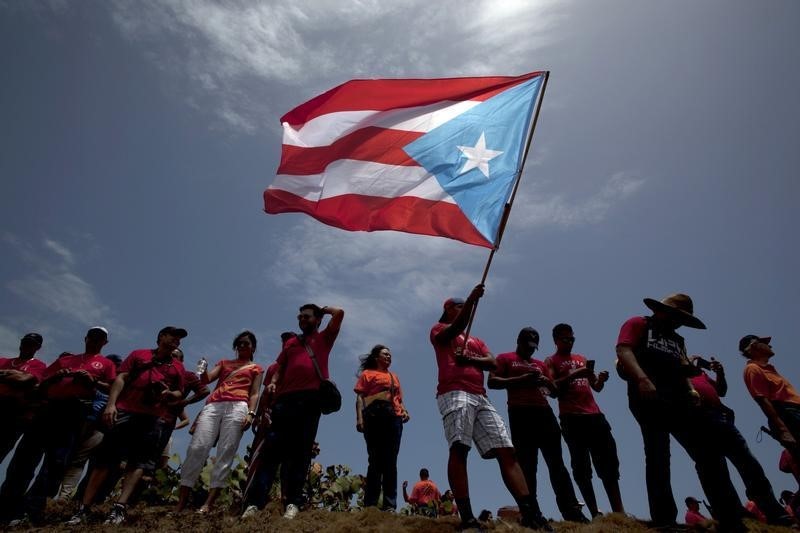 © Reuters. A man waves a national flag as others stand nearby during a protest in San Juan