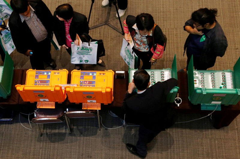 © Reuters. People take a look at Thailand Election Commission's voting machines during an event to kick off the distribution of five million copies of a controversial military-written draft constitution in Bangkok