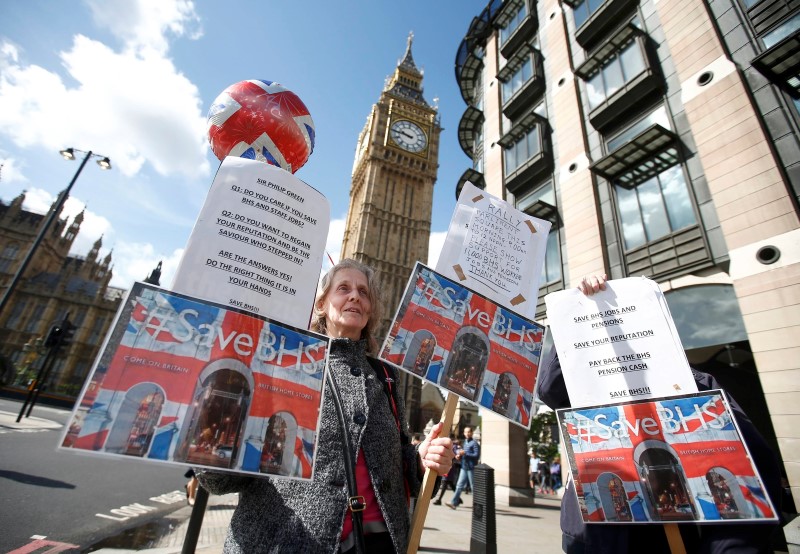 © Reuters. Demonstrators hold placards as they protest against Philip Green, the former owner of retailer British Home Stores, as he gives evidence to the business Parliamentary select committee on the sale and collapse of his former business, in London