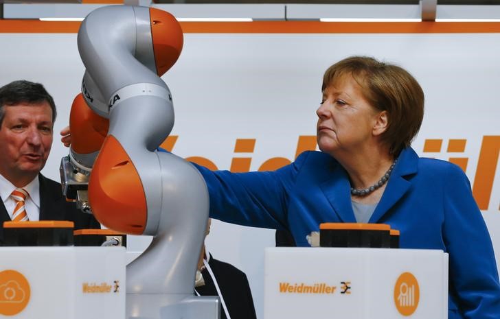 © Reuters. German Chancellor Merkel watches the work of KUKA robot during the opening tour at the Hannover Messe in Hanover