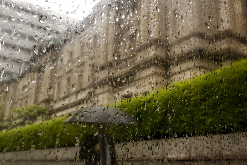 © Reuters. Raindrops run down a window pane as a businessman walks past the Bank of Japan headquarters in Tokyo