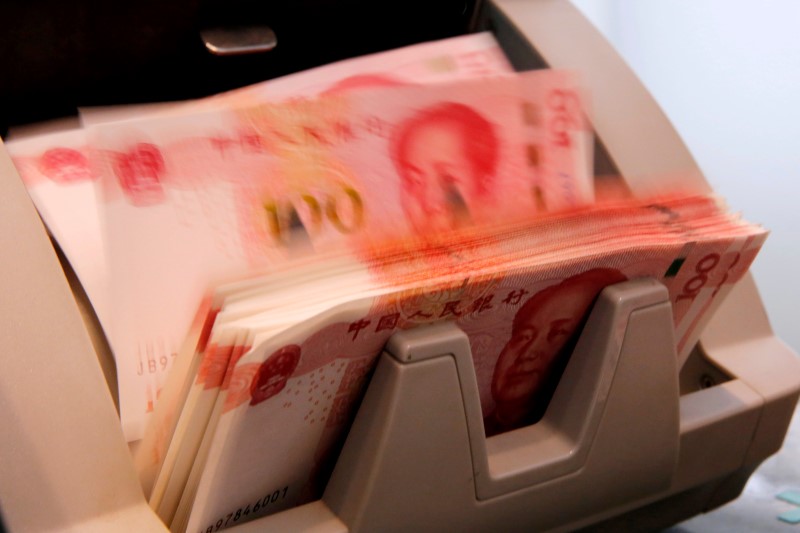 © Reuters. Chinese 100 yuan banknotes are seen in a counting machine while a clerk counts them at a branch of a commercial bank in Beijing