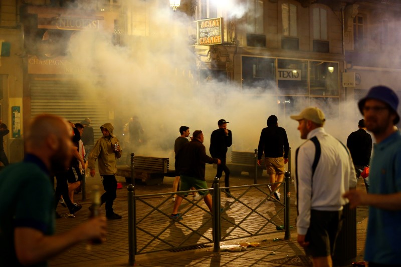 © Reuters. England fans run through tear gas in Lille - Euro 2016