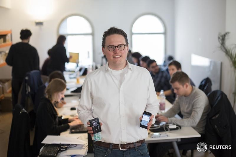 © Reuters. Konstantin Wolff, co-founder of the Payleven credit card payment startup holds his company's card reading device as he poses for pictures in front of his staff in Berlin