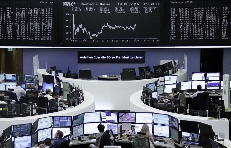 © Reuters. Traders work at their desks in front of the German share price index, DAX board, at the stock exchange in Frankfurt