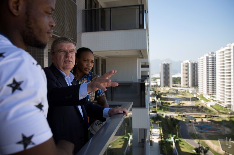 © Reuters. IOC President Bach, center, talks with refugees and judo athletes from the Democratic Republic of Congo Mabika, and Misenga as they visit an apartment at the Olympic Village in Rio de Janeiro