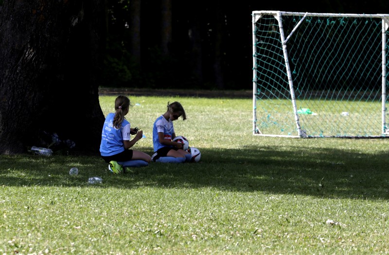 © Reuters. Children rest in the shade under an oak tree in the middle of  soccer pitch in Orissaare
