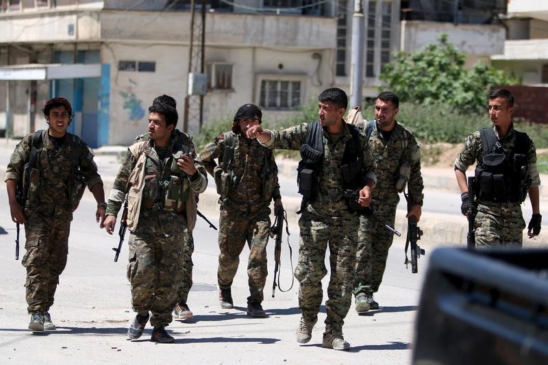 © Reuters. Kurdish fighters from the People's Protection Units (YPG) walk along a street in the southeast of Qamishli city