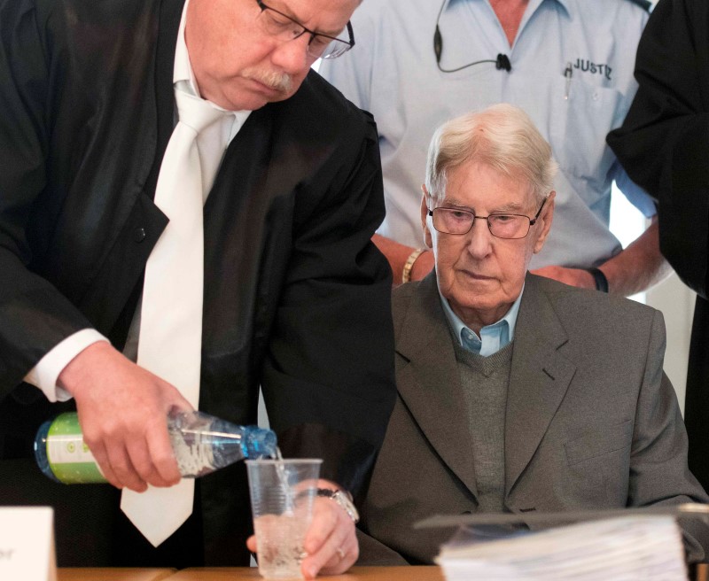 © Reuters. Defendant Hanning, a 94-year-old former guard at Auschwitz death camp, receives a glass of water from his lawyer Scharmern in a courtroom before the continuation of his trial in Detmold