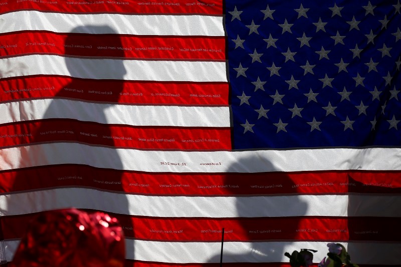 © Reuters. The names of Pulse night club shooting victims are embroidered on a U.S. flag at a makeshift memorial in Orlando