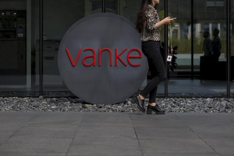 © Reuters. An employee walks past a logo of Vanke at its headquarters in Shenzhen