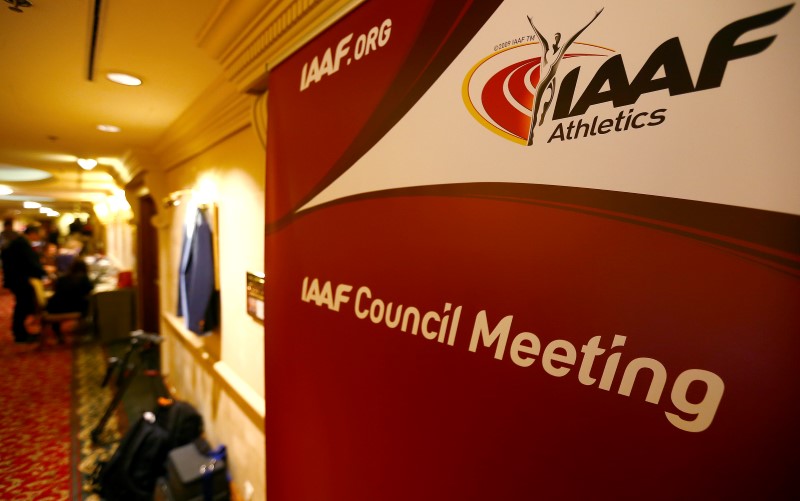 © Reuters. Journalists are seen near a logo of the IAAF at a hotel where the IAAF council holds a meeting in Vienna