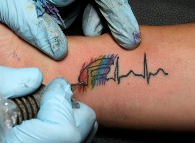 © Reuters. Becky Roero gets a tattoo done by Ron Rivera at Stigma Tattoo Bar to raise funds for the families of the victims who were killed at the Pulse gay nightclub in Orlando