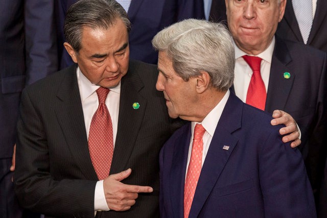 © Reuters. Chinese Foreign Minister Wang Yi speaks with US Secretary of State Kerry as posing for a group photo prior to an international meeting in a bid to revive the Israeli-Palestinian peace process in Paris