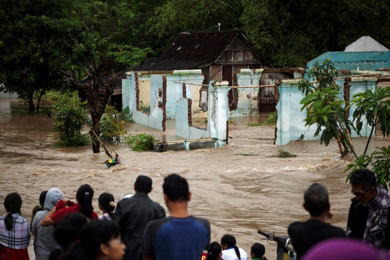 © Reuters. People stand in front of a flooded area in Kampung Sewuresidential area in Solo