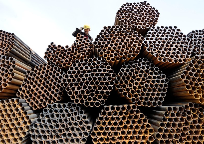 © Reuters. A labourer is seen on top of steel pipes at a steel market in Taiyuan